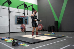 Male weightlifter on platform dropping bar in celebration.