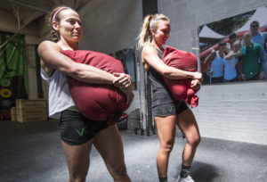 Two female athletes doing sandbag carries.