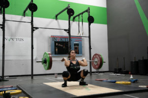 Male athlete wearing a singlet in the bottom on the weightlifting platform.