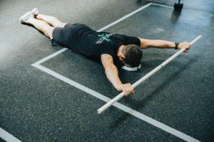 Face-down athlete does PVC passthroughs.