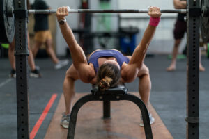 Female athlete unracking a bench press.