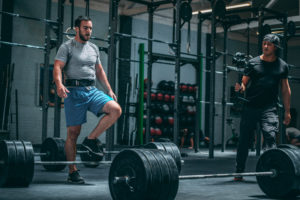 Male athlete wearing a lifting belt stepping over his deadlift bar.