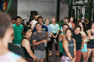 Group fitness class gathers around an athlete who is laughing and talking.