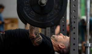 Man doing a bench press and getting really strong because he's following Invictus total strength